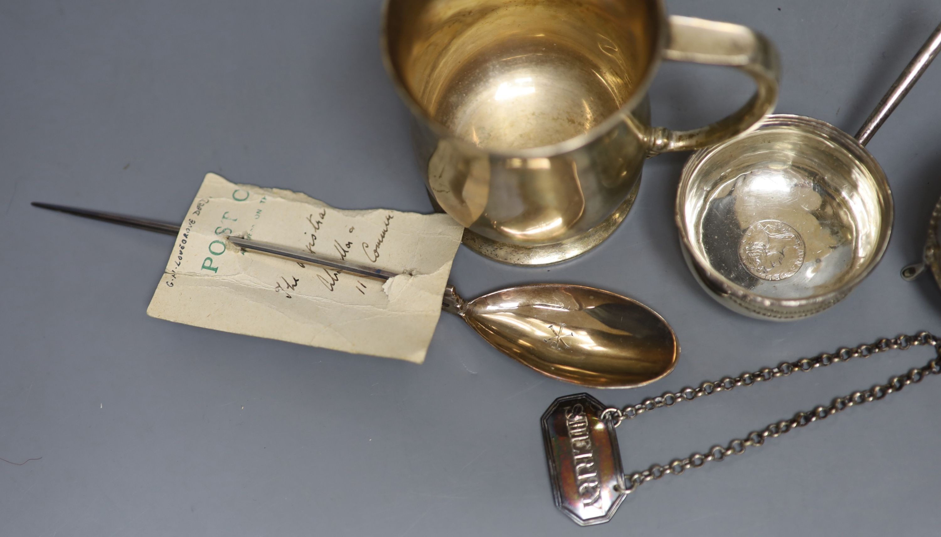 A George V silver mug, a white metal toddy ladle bowl, an Edwardian silver trinket box, a silver reproduction Roman spoon and a George III 'Sherry' label.